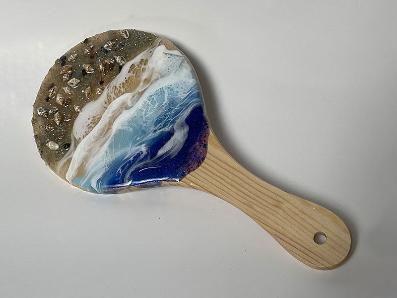 Handheld mirror with seascape theme on back